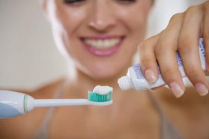 girl putting toothpaste on toothbrush